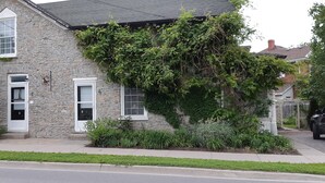 A stone building with a door labeled "BARBICCHIO," windows, and a garden with various plants.
