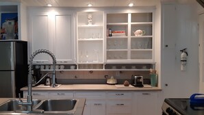 A kitchen with white cabinets, a stainless steel refrigerator, a sink with a modern faucet, and a stove.