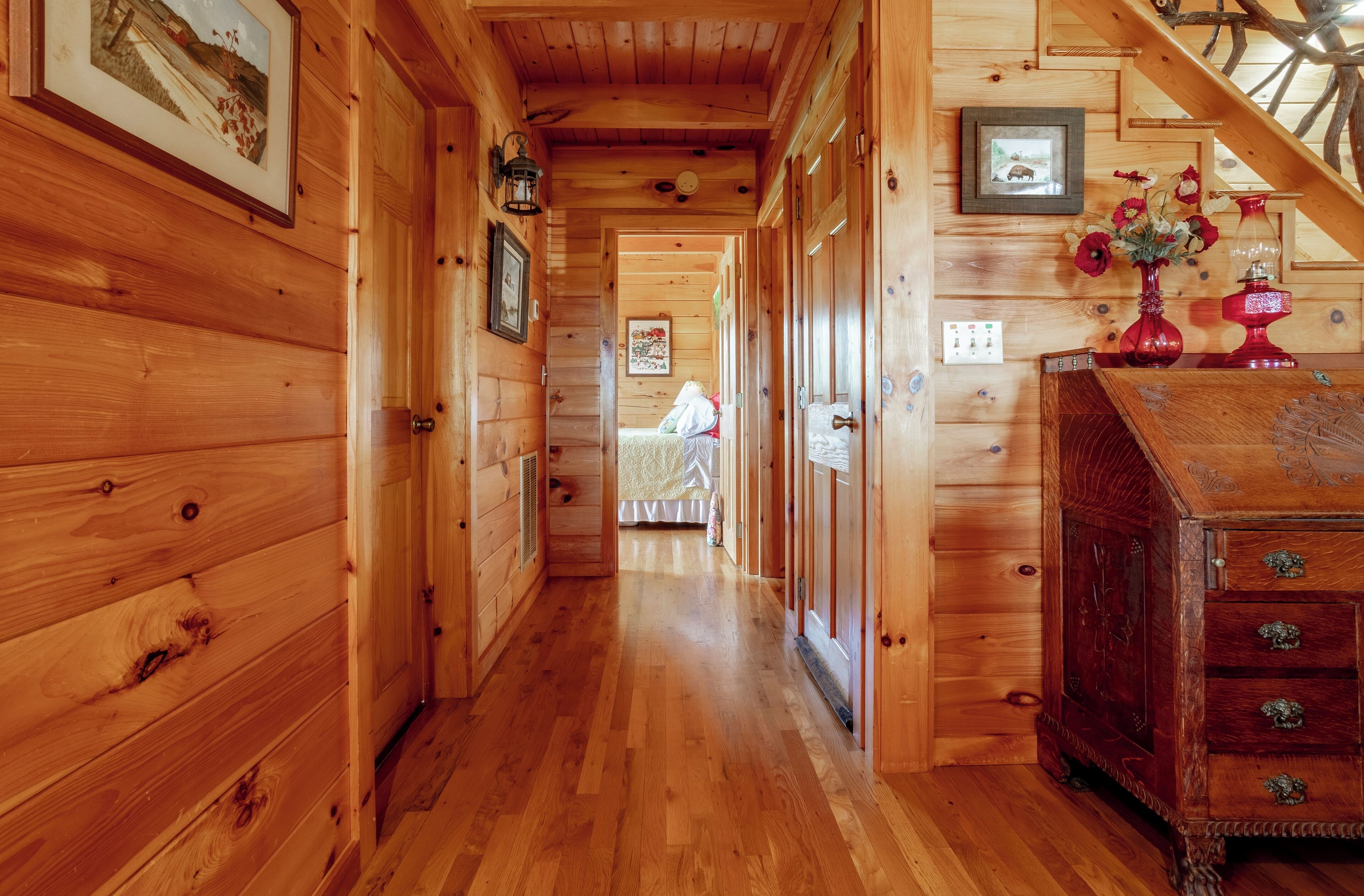 A wooden hallway with a staircase, wooden walls, and a dresser with drawers.