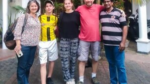 A group of people standing in a courtyard with palm trees and a building in the background. - Myr-o Homestay (Anuradhapura)
