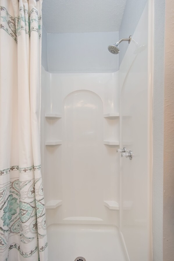 Ducha con cabezal de ducha de mano, bañera blanca y cortina de ducha con estampado de cachemir.