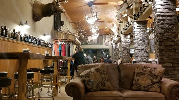 Et værelse med træloft, monterede trofæer, en bar og en sofa.