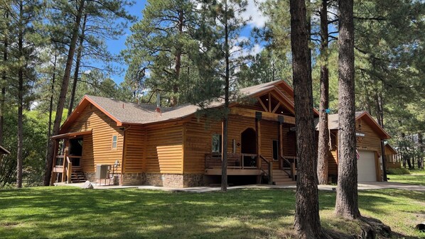 A log cabin with a porch, a chimney, and a garage. - Big Log Cabin Home, Large Back Deck Overlooking Cedar Creek ~ Close To Downtown (Ruidoso)