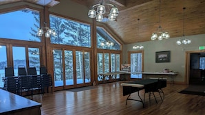 A spacious room with large windows, wooden floors, and hanging pendant lights. - Historic Lodge on 48 Acres Overlooking Long Lake Updated for Accessibility (Walker)