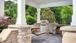 An outdoor patio with stone walls, a grill, and a covered seating area. - Spacious Upscale Condo,  Monthly Rates Available October- April,  Call Owner (Southport)