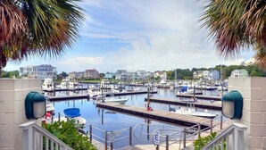 A marina with boats docked, a wooden deck, and a view of houses in the background. - Spacious Upscale Condo,  Monthly Rates Available October- April,  Call Owner (Southport)
