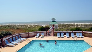 A pool area with lounge chairs, a no-smoking sign, and a view of the ocean. - Spacious Upscale Condo,  Monthly Rates Available October- April,  Call Owner (Southport)