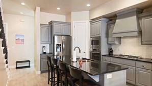 A modern kitchen with grey cabinets, stainless steel appliances, and a central island with bar stools. - Good Day Sunshine 2 COMMUNITY POOLS, Location!! (Washington)