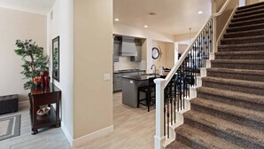 A spacious living area with a kitchen in the background, a staircase with a railing, and a dining area with chairs. - Good Day Sunshine 2 COMMUNITY POOLS, Location!! (Washington)