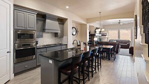 A modern kitchen with a central island, stainless steel appliances, and a dining area with bar stools. - Good Day Sunshine 2 COMMUNITY POOLS, Location!! (Washington)