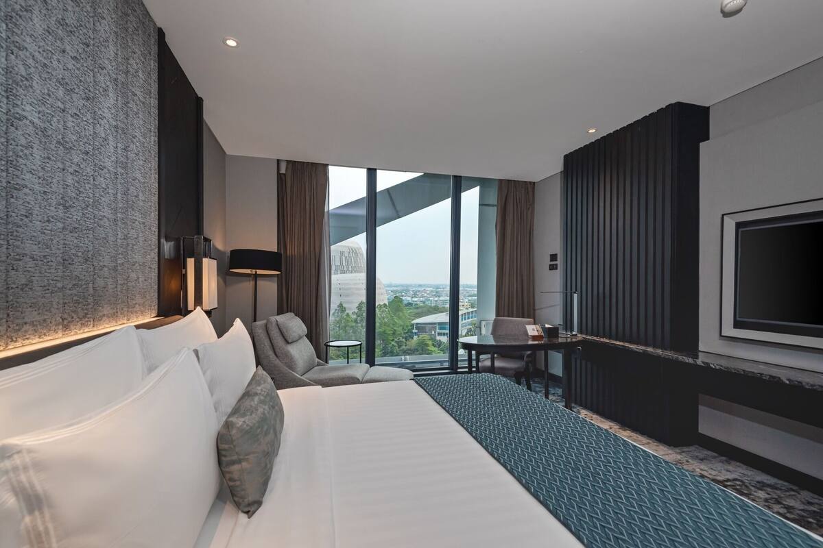 A modern hotel room with a large bed, a desk, and a TV.