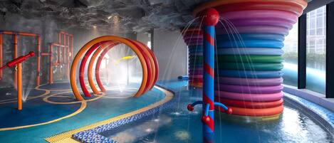 Un'area giochi acquatici al chiuso con scivoli colorati e giochi d'acqua.