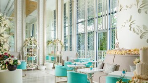 Una habitación amplia con muebles azul turquesa y blancos, ventanas grandes y decoración floral.