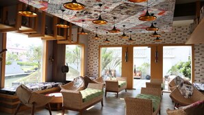 A spacious indoor area with wicker furniture, pendant lighting, and a patterned ceiling. - Pramod Convention & Beach Resort (Puri)