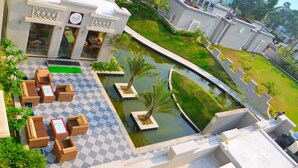 A hotel with outdoor seating, a pool, and a well-maintained garden. - Pramod Convention & Beach Resort (Puri)
