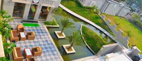 A hotel with outdoor seating, a pool, and a well-maintained garden.
