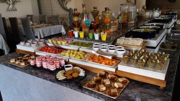 Un bufé con diferentes opciones de comida, como frutas, pasteles y sándwiches.