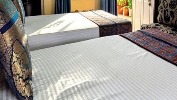 A hotel room with a bed, a sofa, a window with curtains, and a door. - Tara Guest House (Varanasi)