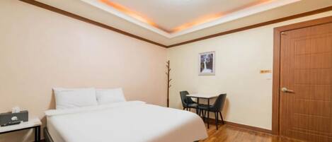 Una habitación de hotel con cama, escritorio, silla y puerta.