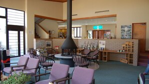 A lobby with purple chairs, a central fireplace, and a brick wall with a sign.