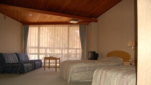 A bedroom with two beds, a sofa, a television, and a small table.
