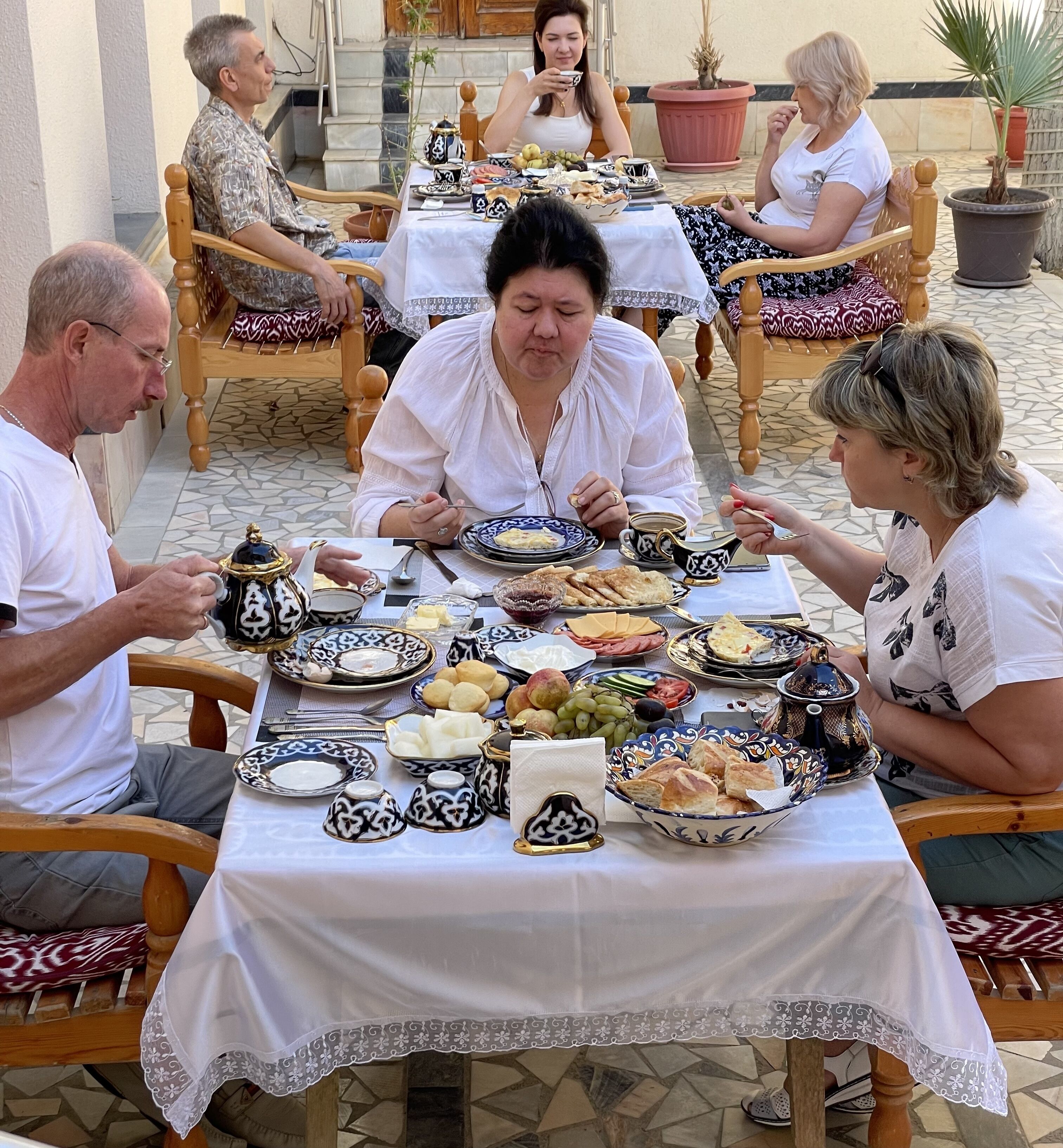 Un groupe de personnes est assis autour d’une table, devant une variété de plats et de boissons, ce qui laisse supposer qu’il s’agit d’un rassemblement social ou d’un repas.