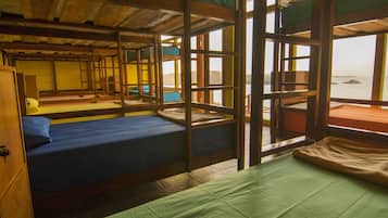 A traditional Japanese-style room with tatami mat flooring, wooden beams, and a view of the sea through large windows.