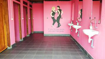 A restroom with pink walls, two sinks, and a mural of two people.