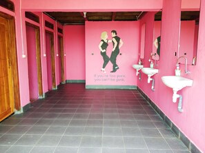 A restroom with pink walls, two sinks, and a mural of two people. - One Tree Hill - Hostel (Labuan Bajo)