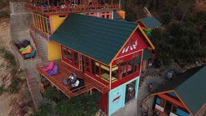 A multi-story building with a green roof, multiple balconies, and a large windowed area. - One Tree Hill - Hostel (Labuan Bajo)