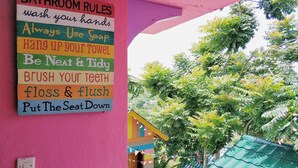 A colorful bathroom rules sign on a pink wall. - One Tree Hill - Hostel (Labuan Bajo)