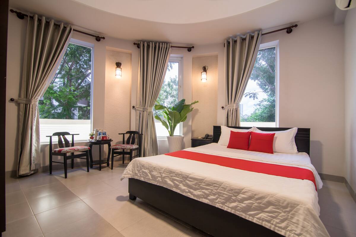 Ein Hotelzimmer mit einem großen Bett, zwei Stühlen, einem kleinen Tisch und einer Zimmerpflanze.