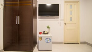 Una habitación con armario, refrigerador pequeño, televisión y puerta.