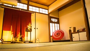A traditional Japanese room with tatami flooring, sliding doors, and a red decorative fan. - Oyado Toji 3 (Kyoto)