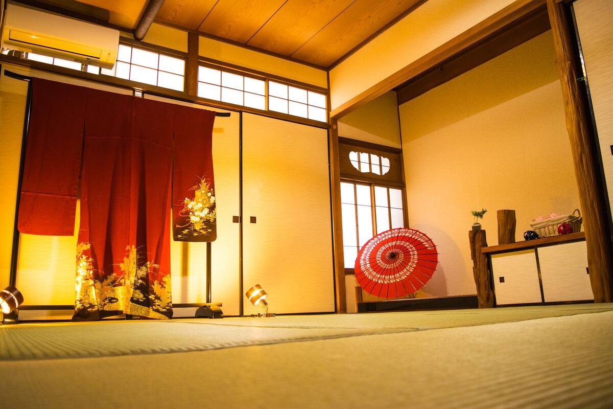 A traditional Japanese room with tatami flooring, sliding doors, and a red decorative fan.