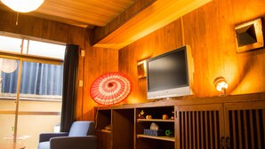 A wooden-paneled room with a television, a red umbrella, and a lamp. - Oyado Toji 3 (Kyoto)