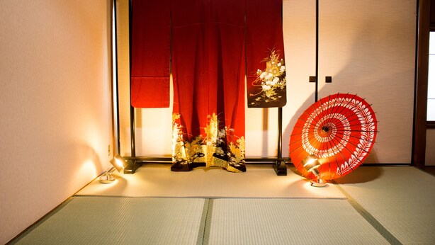 A traditional Japanese room with tatami flooring, a red sliding door, and a decorative umbrella. - Oyado Toji 3 (Kyoto)