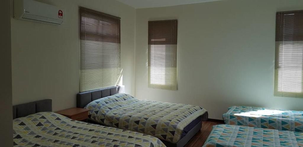 A room with two beds, a small table, and a window with blinds.