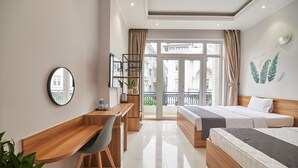 A modern hotel room with a wooden desk, a bed with two pillows, a small seating area, and a balcony with a view of the city. - Bin Bin Hotel 2 - Near Him Lam D7 (Ho Chi Minh City)