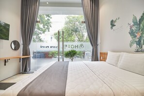 A hotel room with a bed, curtains, a mirror, a bedside table, and a view of the street outside. - Bin Bin Hotel 2 - Near Him Lam D7 (Ho Chi Minh City)