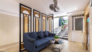 A modern lobby with a blue sofa, a glass coffee table, and a potted plant. There is a staircase leading to another level and a door with a frosted glass panel. - Bin Bin Hotel 2 - Near Him Lam D7 (Ho Chi Minh City)