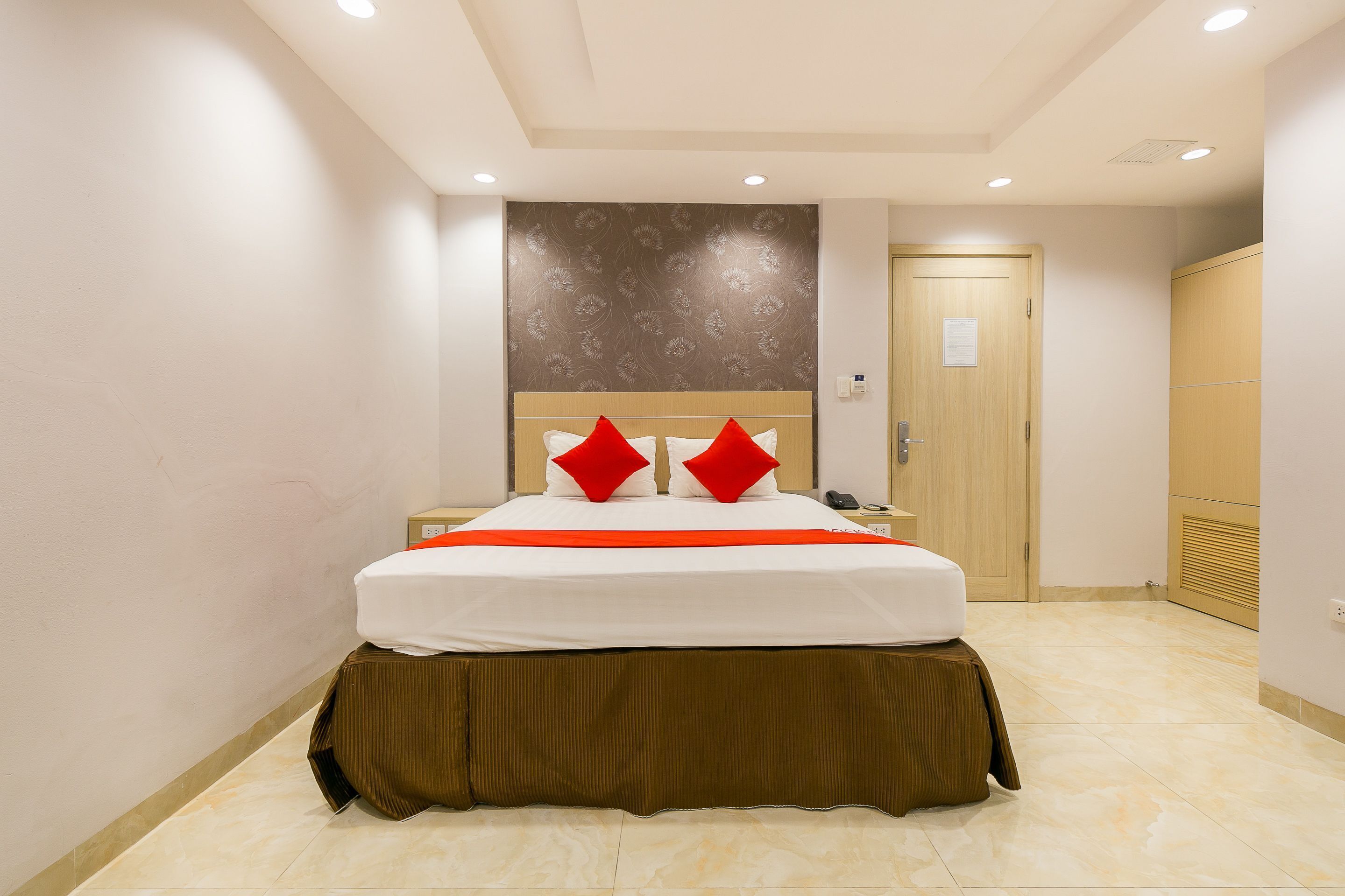 Une chambre d’hôtel avec un lit, une table de chevet, une porte en bois et une armoire.