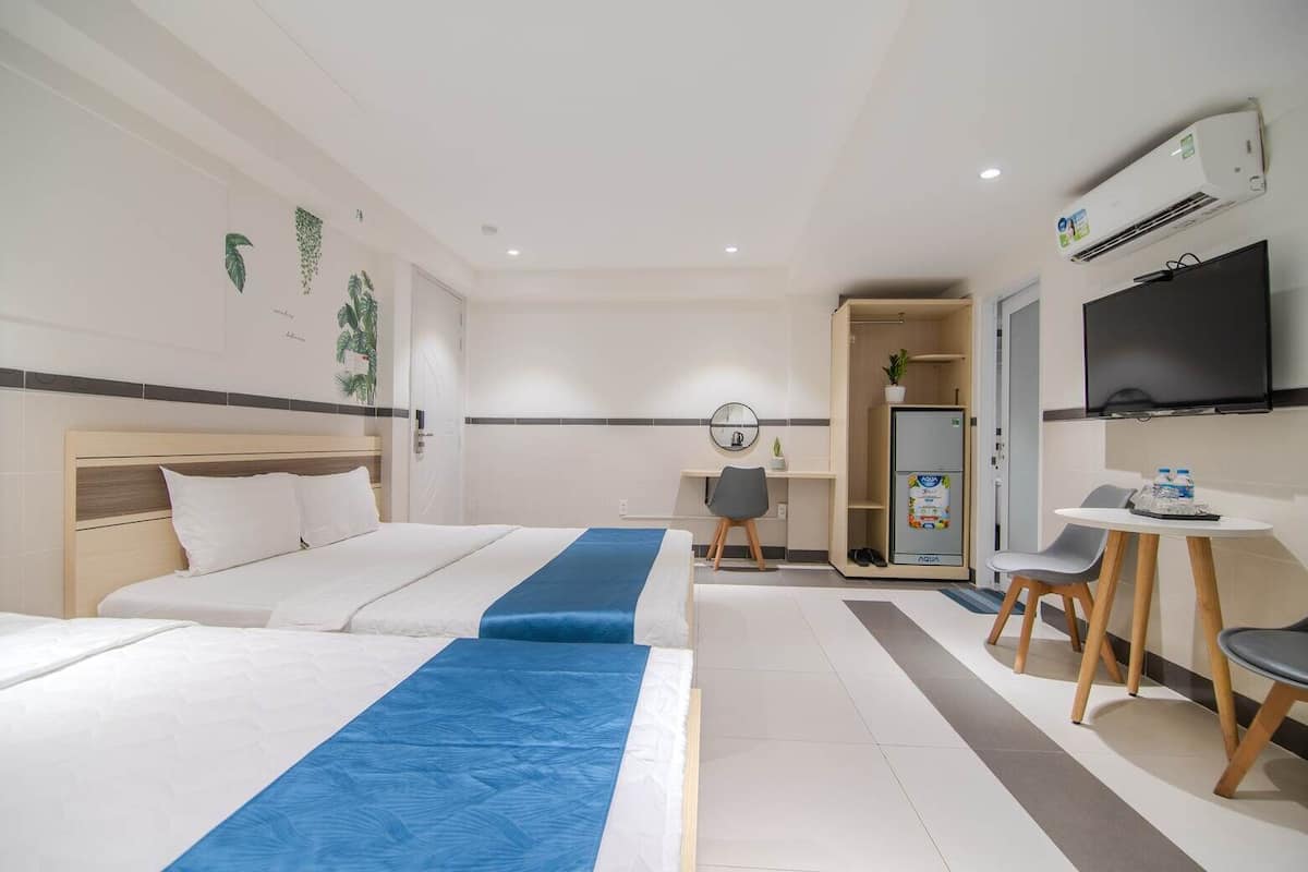 A hotel room with a large bed, a desk with a chair, a television, and a minibar.