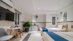 A hotel room with two beds, a dining table with chairs, a TV, a small kitchen area, and a potted plant. - BinBin Hotel 5 - Near Lotte Mart D7 (Ho Chi Minh City)