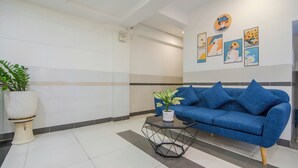 A modern waiting area with a blue sofa, a geometric coffee table, and a potted plant. - BinBin Hotel 5 - Near Lotte Mart D7 (Ho Chi Minh City)