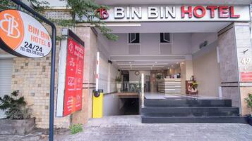 The entrance to Bin Bin Hotel with a clear sign, a staircase leading inside, and a reception area visible through the glass doors.