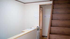 Una escala de fusta que porta a una habitació amb barana de fusta i un petit escriptori ple de papers.
