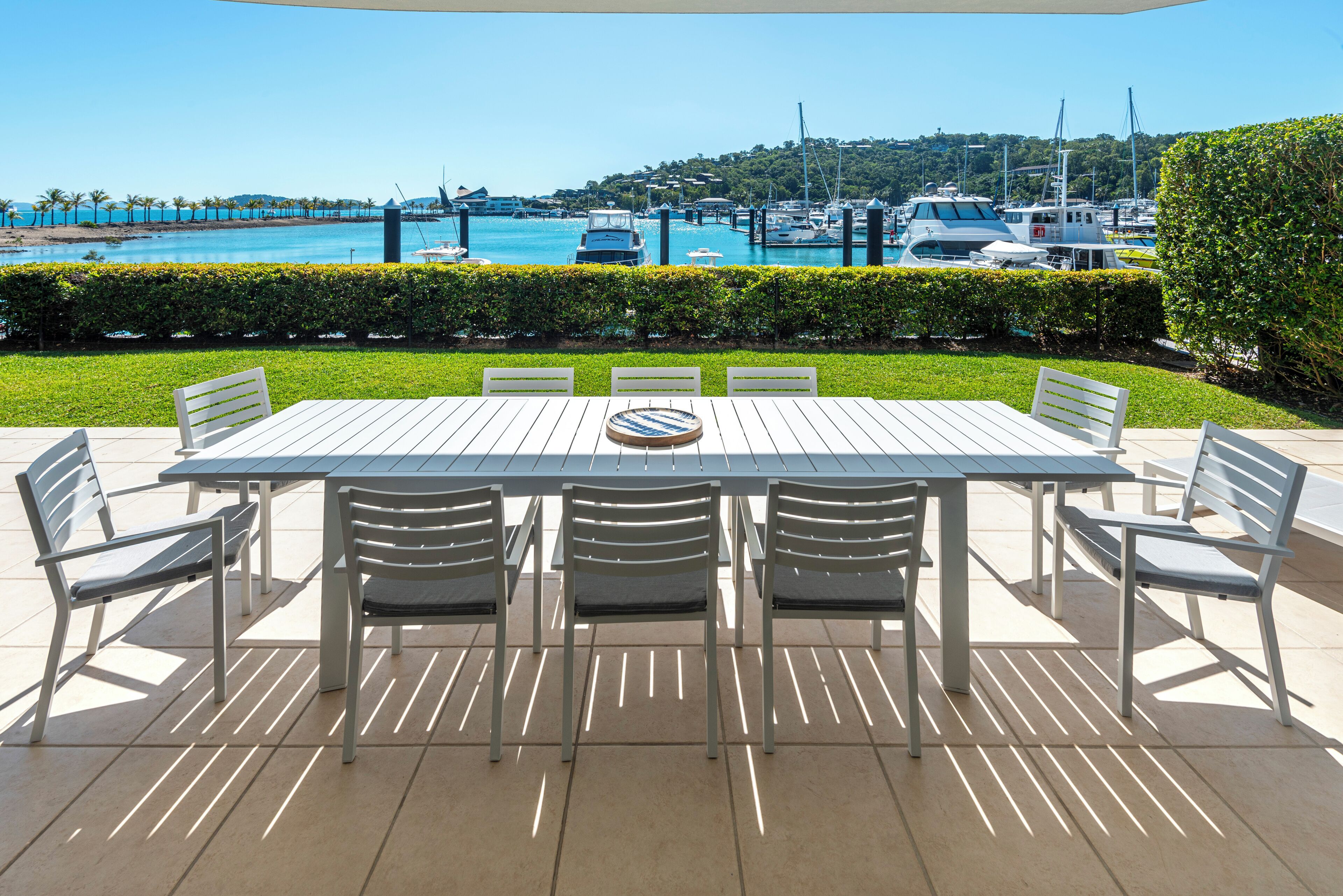 A table and chairs set outdoors with a view of a marina and boats.