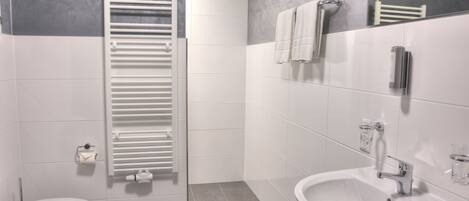 Un baño moderno con inodoro, un lavamanos blanco, un toallero y una toalla colgada en la pared.