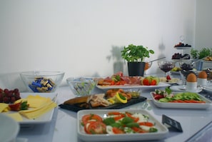 Una mesa de buffet con diversos alimentos, como frutas, quesos, carnes y ensaladas.